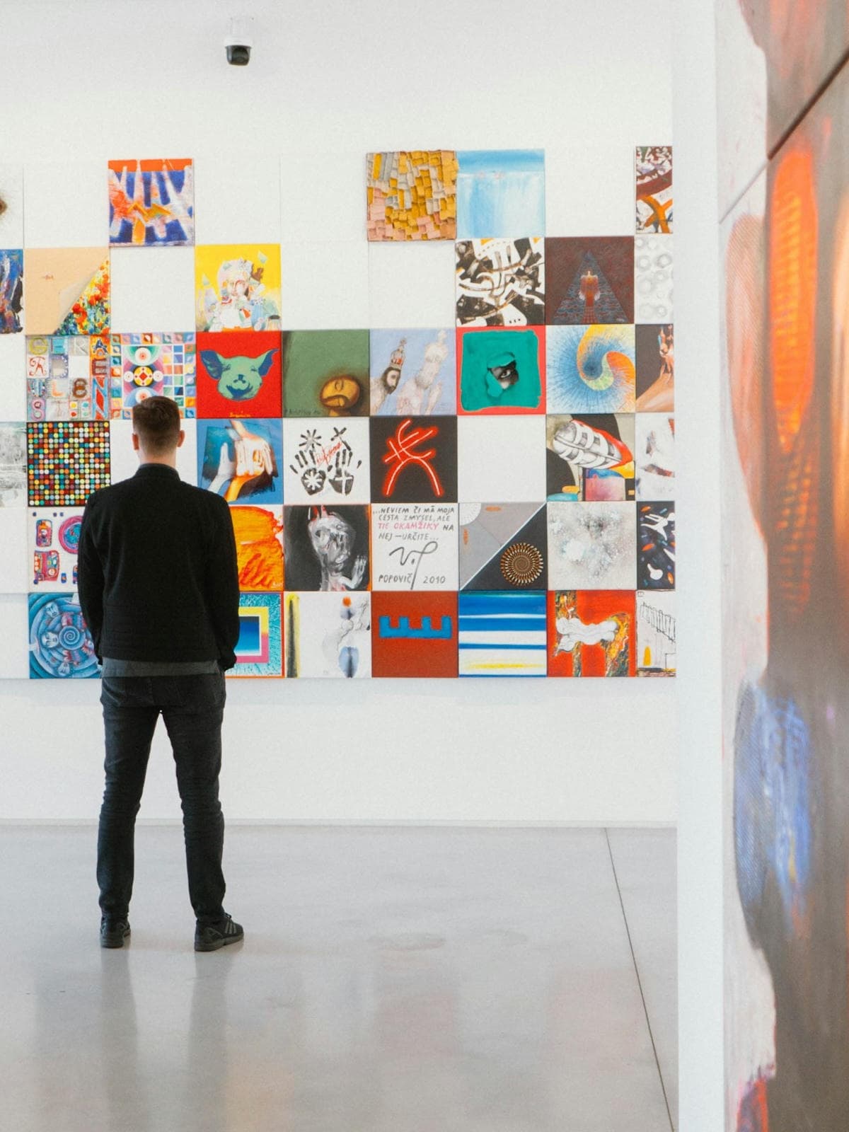 Visitor viewing a wall of contemporary artworks in a gallery